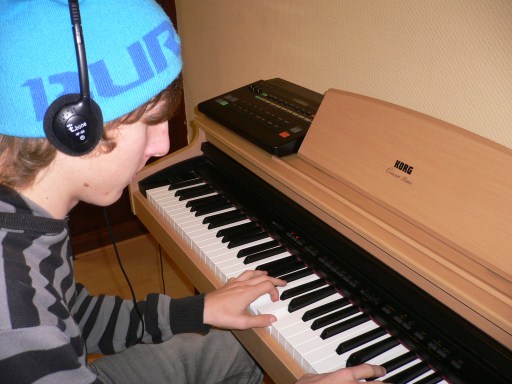 Junger Schüler mit Kopfhörern am Digitalpiano im Willicher Musikhaus