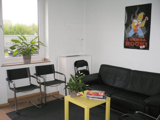 Wartebereich des Willicher Musikhauses mit Sofa, Pflanzen und gelbem Tisch